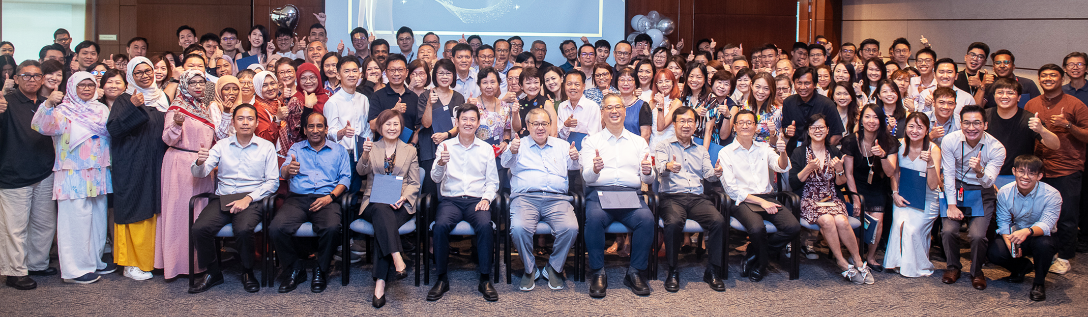 Large group photo of URA staff in a function hall.